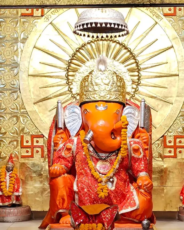 Shri Ganesh ji idol in orange sindoor with gold backdrop